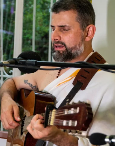 Pierre Clemente conduzindo kīrtan ao violão